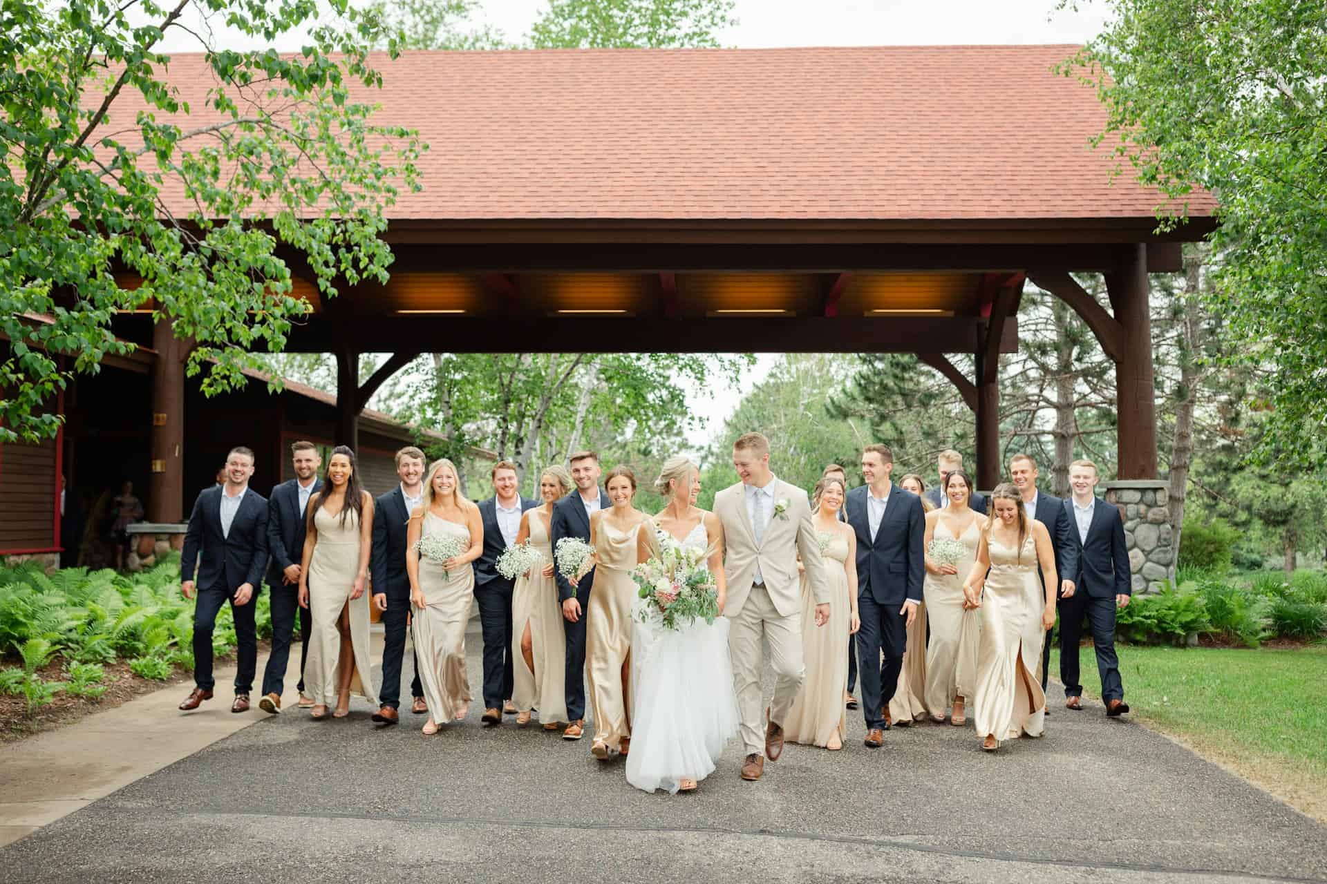 Beautiful wedding party walking outdoors at Zolana Weddings, featuring bridesmaids, groomsmen, and bride and groom.