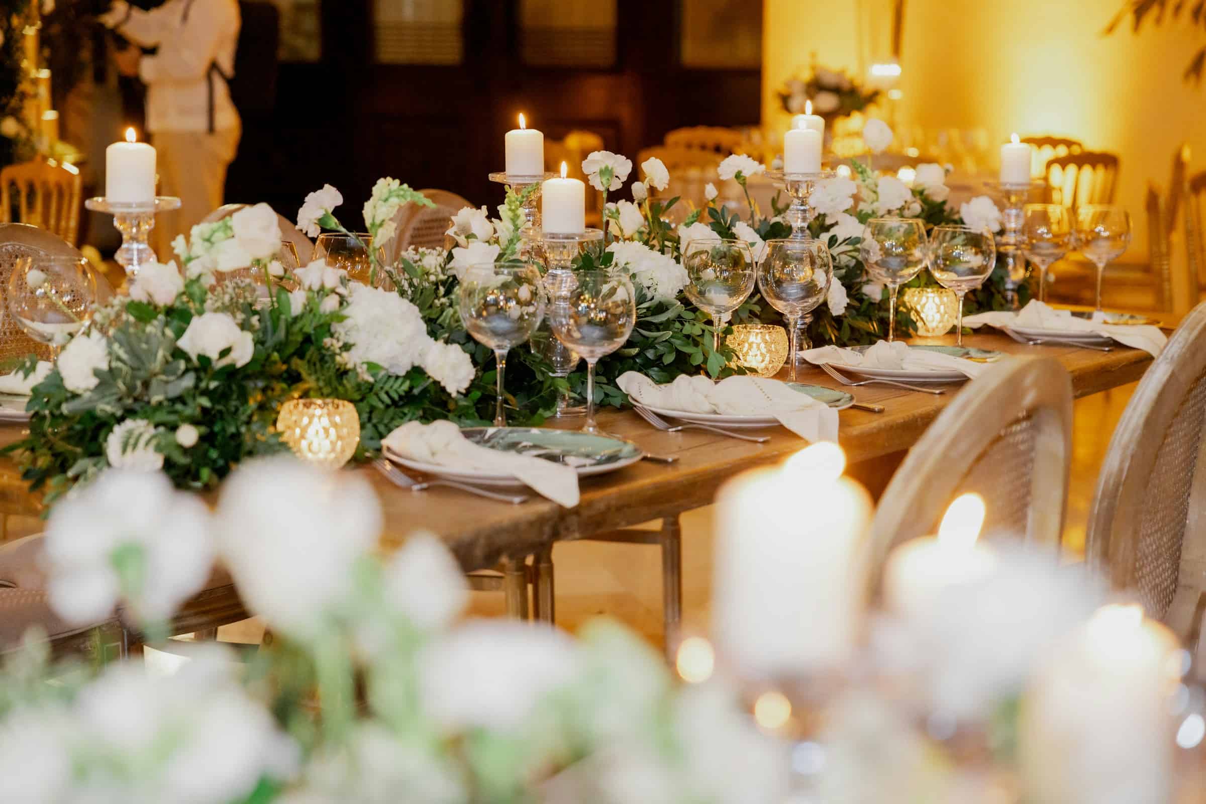 Luxurious wedding reception table with white flowers, candles, and fine glassware.