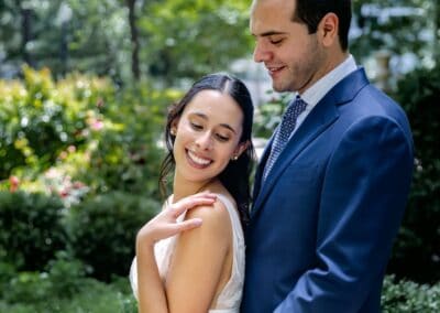 Beautiful bride and groom smiling in lush outdoor setting, capturing romantic wedding moment.