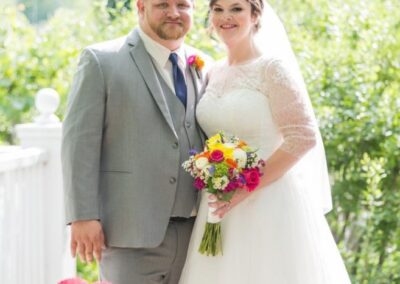 Beautiful bride and groom at an outdoor wedding surrounded by lush greenery.
