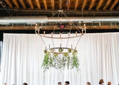 Chic wedding ceremony with bride and groom, surrounded by wedding party in a modern, rustic venue.